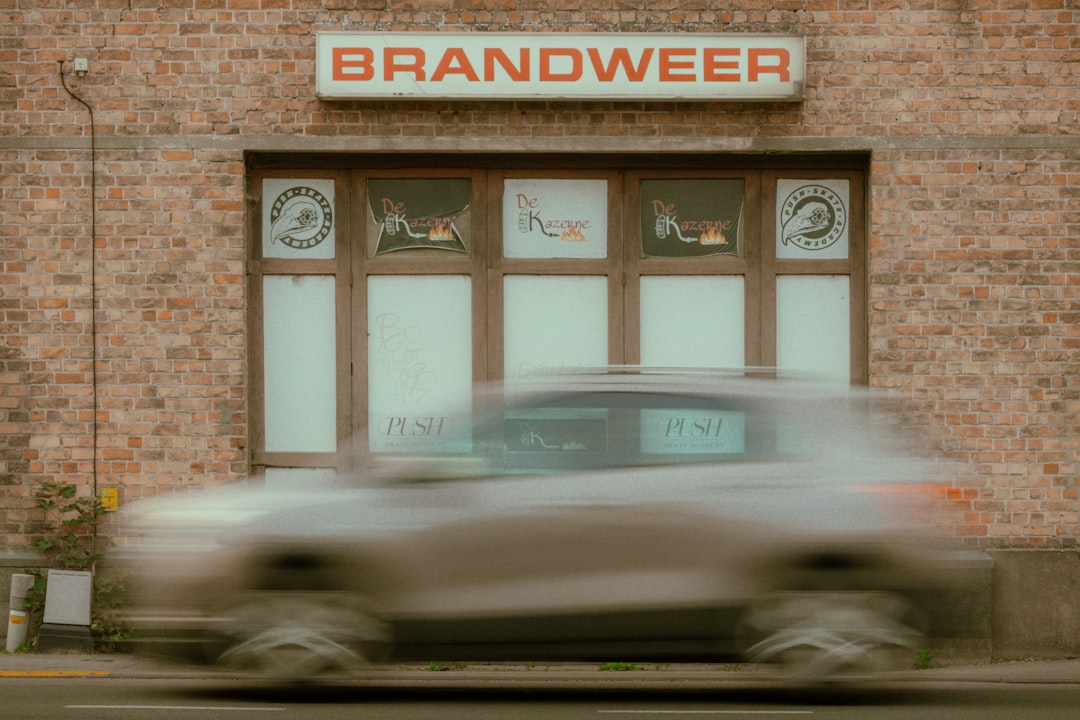 A blurred car passes a building labeled 