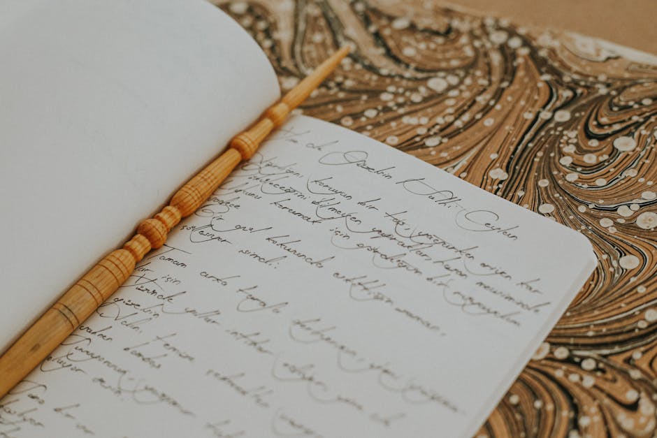 Open notebook with cursive handwriting and a wooden pen on a marbled background.