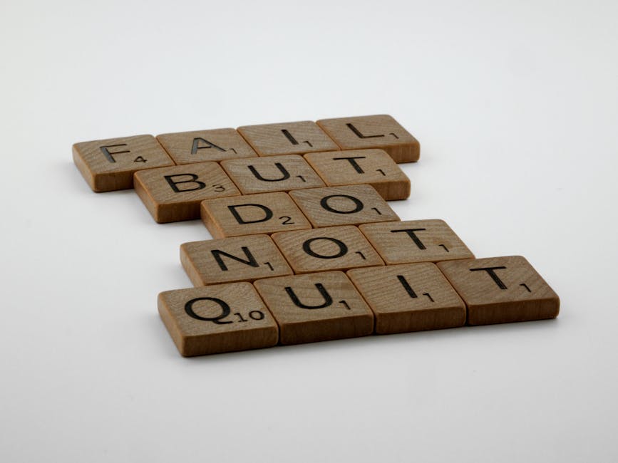 Wooden Scrabble tiles arranged to spell 'Fail but do not quit,' inspiring determination.