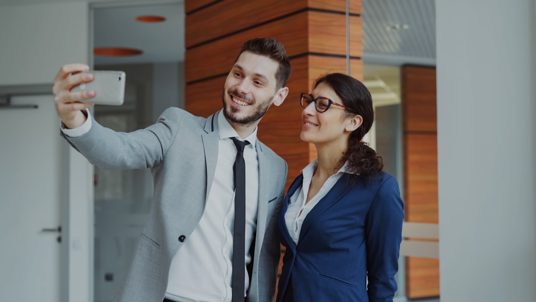Man and woman taking a selfie in office building.